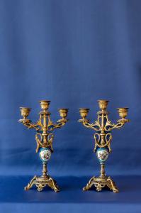 Coppia di candelieri in metallo dorato e porcellana dipinta a fiori a tre luci