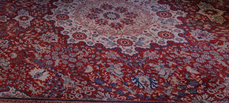 Tappeto persiano a fondo rosso e motivi floreali in blu